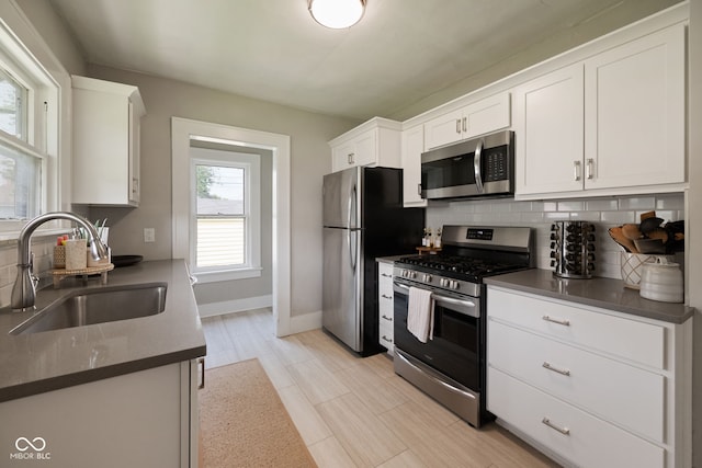 536 S 27th St, Lafayette, IN 47904 - kitchen featuring stainless steel appliances, a sink, decorative backsplash, white cabinetry, and baseboards