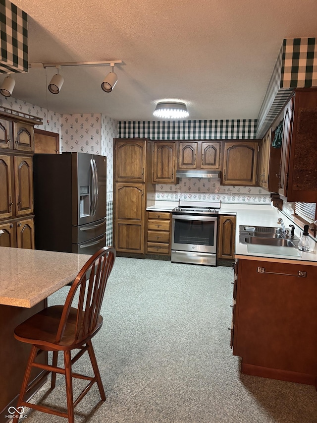 505 N Edward Dr, Greensburg, IN 47240 - kitchen with appliances with stainless steel finishes, a sink, wallpapered walls, under cabinet range hood, and light countertops