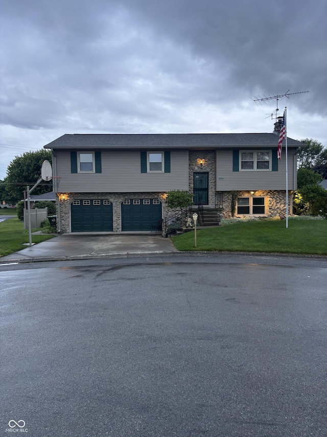 505 N Edward Dr, Greensburg, IN 47240 - split foyer home with stone siding, an attached garage, asphalt driveway, and a front lawn