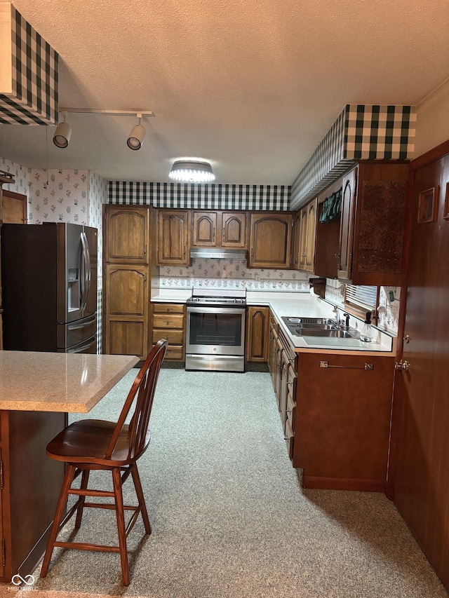 505 N Edward Dr, Greensburg, IN 47240 - kitchen with appliances with stainless steel finishes, wallpapered walls, light countertops, under cabinet range hood, and a sink