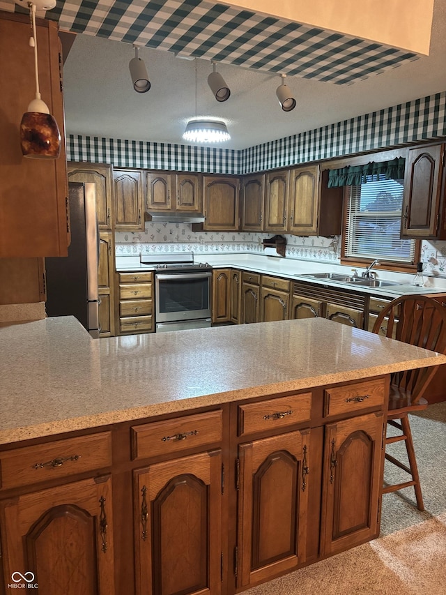 505 N Edward Dr, Greensburg, IN 47240 - kitchen with stainless steel appliances, a sink, under cabinet range hood, a peninsula, and light colored carpet
