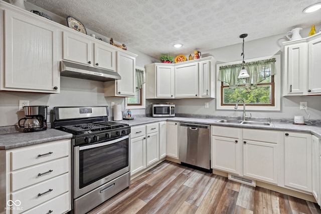 7441 State Road 60 W, Mitchell, IN 47446 - kitchen with under cabinet range hood, appliances with stainless steel finishes, a sink, white cabinets, and a textured ceiling