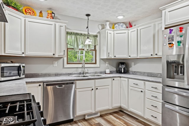 7441 State Road 60 W, Mitchell, IN 47446 - kitchen with stainless steel appliances, a sink, white cabinetry, light countertops, and a textured ceiling