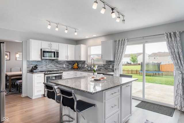3638 Fieldstone Ln, Plainfield, IN 46168 - kitchen with appliances with stainless steel finishes, backsplash, light stone countertops, track lighting, and light wood-type flooring