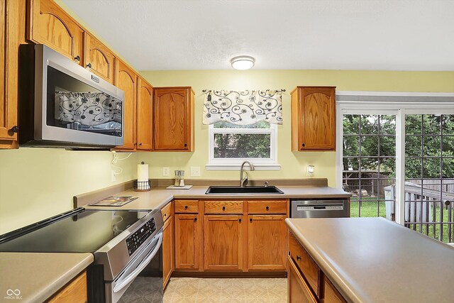 2623 Senators Way, Indianapolis, IN 46217 - kitchen with appliances with stainless steel finishes, a sink, brown cabinetry, light countertops, and light flooring