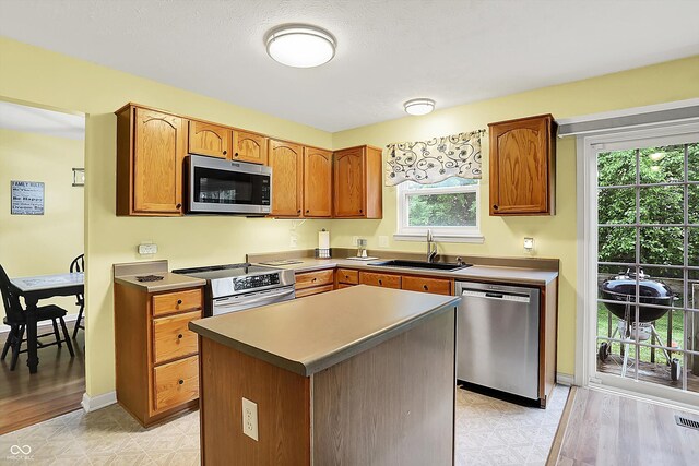 2623 Senators Way, Indianapolis, IN 46217 - kitchen featuring stainless steel appliances, a sink, light flooring, brown cabinets, and a kitchen island