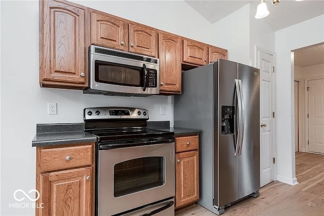 6707 Dovir Woods Dr, Sellersburg, IN 47172 - kitchen featuring appliances with stainless steel finishes, light wood-style floors, dark countertops, and brown cabinetry