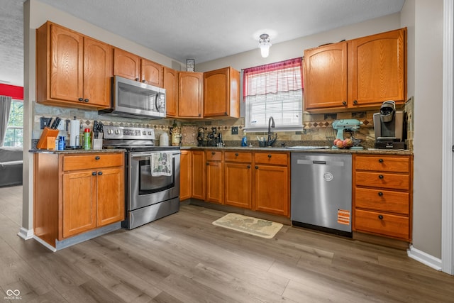 2730 Foxbriar Pl, Indianapolis, IN 46203 - kitchen with stainless steel appliances, a sink, light wood finished floors, backsplash, and a textured ceiling