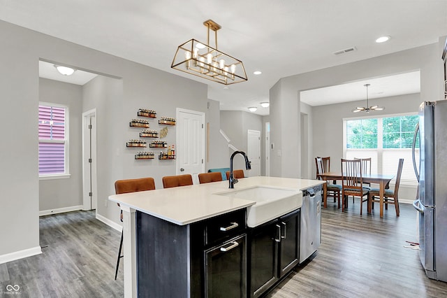 158 Handley St, Indianapolis, IN 46222 - kitchen with appliances with stainless steel finishes, dark cabinets, a sink, a chandelier, and light wood-style flooring