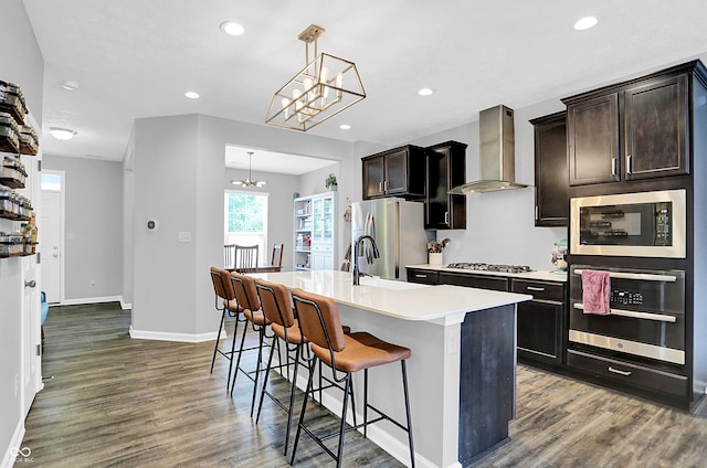 158 Handley St, Indianapolis, IN 46222 - kitchen featuring appliances with stainless steel finishes, wall chimney exhaust hood, wood finished floors, a sink, and a chandelier