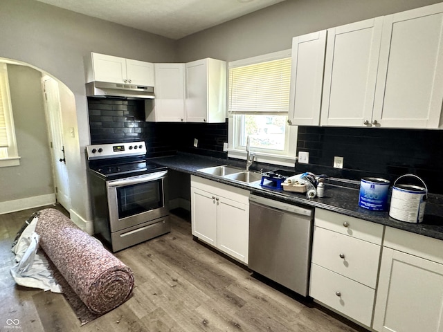 4814 E New York St, Indianapolis, IN 46201 - kitchen with stainless steel appliances, under cabinet range hood, a sink, white cabinets, and tasteful backsplash