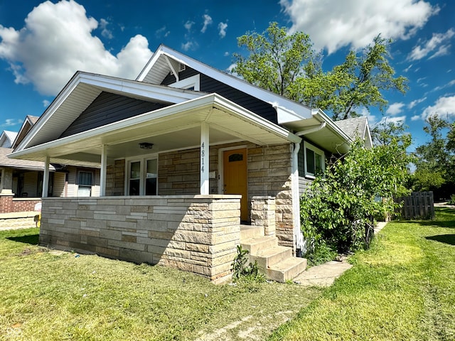 4814 E New York St, Indianapolis, IN 46201 - view of front facade featuring a front lawn, a porch, and stone siding