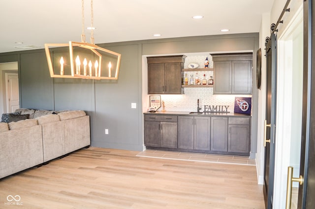 987 Oak Terrace Rd, Westfield, IN 46074 - kitchen with a barn door, a sink, light wood-style floors, a chandelier, and backsplash