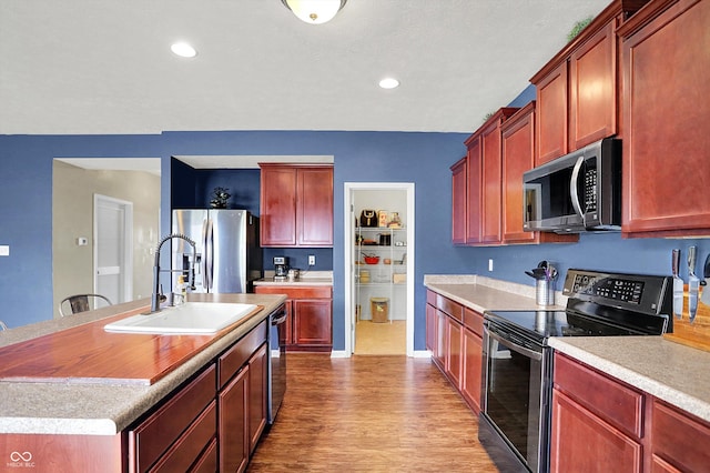 442 Mozart Dr, Greenfield, IN 46140 - kitchen with stainless steel appliances, a sink, wood finished floors, reddish brown cabinets, and recessed lighting
