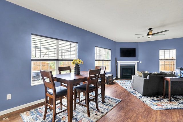 442 Mozart Dr, Greenfield, IN 46140 - dining room featuring a fireplace with flush hearth, wood finished floors, a ceiling fan, and baseboards