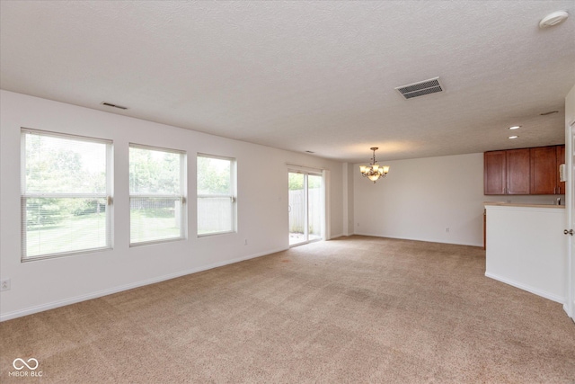 163 Clear Branch Dr, Brownsburg, IN 46112 - unfurnished living room with a chandelier, light colored carpet, a textured ceiling, and baseboards