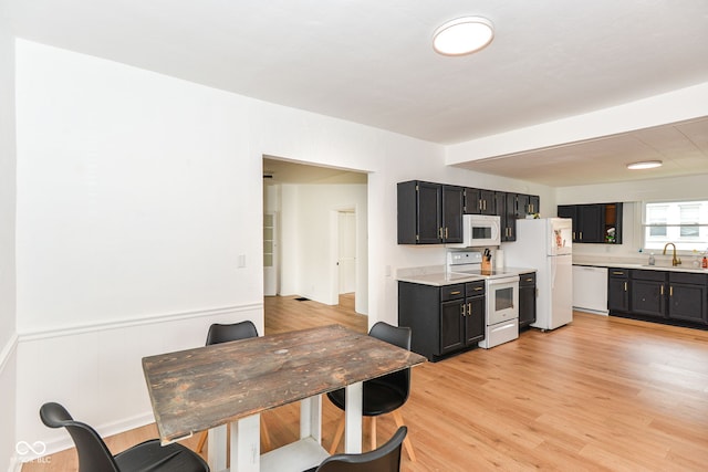 201 N 11th St, Elwood, IN 46036 - kitchen featuring white appliances, light countertops, dark cabinetry, a sink, and light wood-type flooring