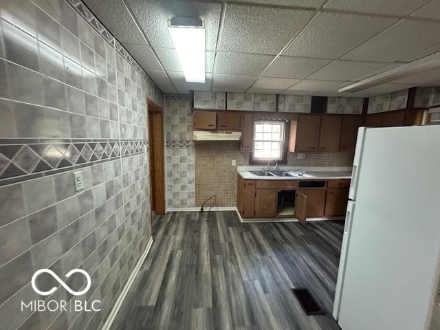 1527 Main St, Beech Grove, IN 46107 - kitchen featuring freestanding refrigerator, under cabinet range hood, a sink, light countertops, and dark wood-style flooring