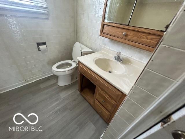 1527 Main St, Beech Grove, IN 46107 - bathroom with tile walls, toilet, vanity, wood finished floors, and backsplash