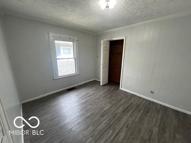 1527 Main St, Beech Grove, IN 46107 - unfurnished bedroom with dark wood-style floors, a textured ceiling, ornamental molding, baseboards, and a closet