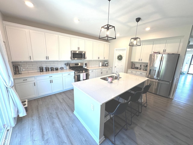 1056 Bent Branch Ln, Greenwood, IN 46143 - kitchen with appliances with stainless steel finishes, light wood-style floors, tasteful backsplash, a kitchen island with sink, and white cabinetry
