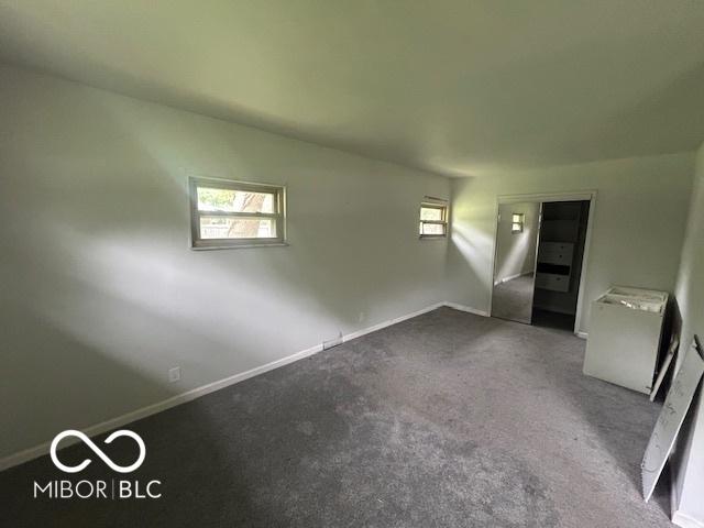 907 Monroe St, Indianapolis, IN 46229 - empty room with plenty of natural light, baseboards, and dark colored carpet