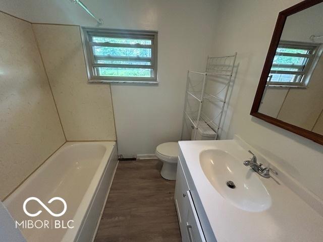 907 Monroe St, Indianapolis, IN 46229 - bathroom featuring vanity, wood finished floors, toilet, baseboards, and shower / bathtub combination