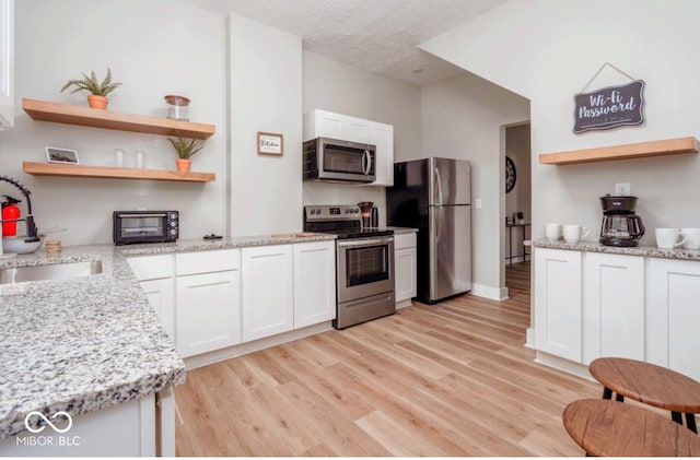 2349 N Capitol Ave, Indianapolis, IN 46208 - kitchen with stainless steel appliances, open shelves, light wood finished floors, white cabinets, and a textured ceiling