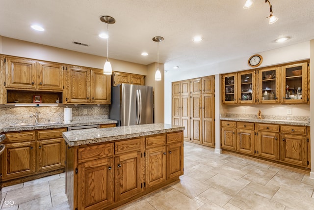 5326 White Marsh Ln, Indianapolis, IN 46226 - kitchen featuring appliances with stainless steel finishes, a sink, brown cabinets, a center island, and backsplash
