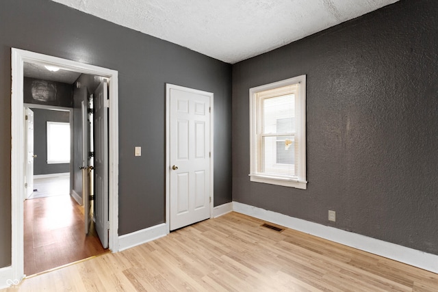 3636 Crescent Ave, Indianapolis, IN 46208 - unfurnished bedroom featuring light wood-type flooring, baseboards, and a textured wall