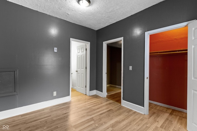 3636 Crescent Ave, Indianapolis, IN 46208 - unfurnished bedroom with wood finished floors, a closet, a textured ceiling, baseboards, and a walk in closet