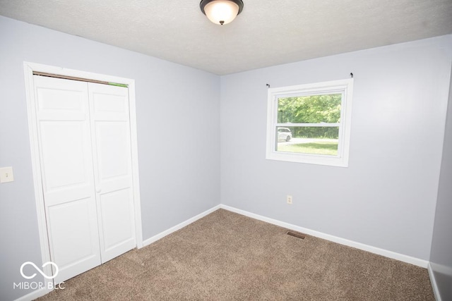 1440 N County Road 275 E, North Vernon, IN 47265 - unfurnished bedroom featuring carpet, a closet, baseboards, and a textured ceiling