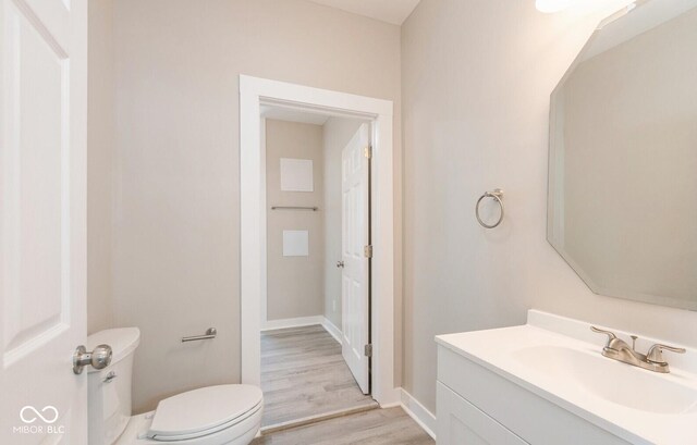 126 W Windsor St, Montpelier, IN 47359 - bathroom with toilet, vanity, wood finished floors, and baseboards