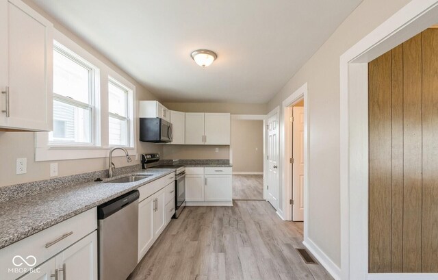 126 W Windsor St, Montpelier, IN 47359 - kitchen with stainless steel appliances, a sink, light wood-style flooring, white cabinetry, and baseboards