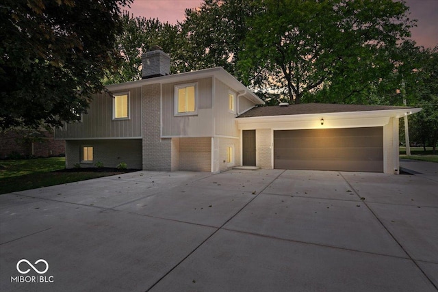 11123 Haverstick Rd, Carmel, IN 46033 - view of front of house featuring concrete driveway, brick siding, a chimney, and an attached garage