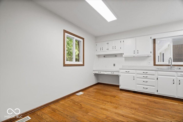 11123 Haverstick Rd, Carmel, IN 46033 - kitchen featuring a sink, light countertops, baseboards, white cabinetry, and light wood finished floors