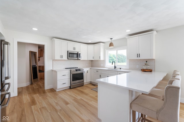 10274 S 400 W, Pendleton, IN 46064 - kitchen featuring stainless steel appliances, a peninsula, a breakfast bar area, light wood-style flooring, and recessed lighting