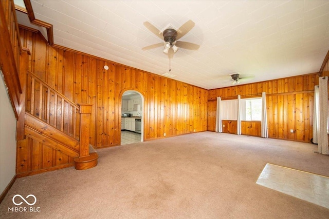 5 E Jefferson St, Maxwell, IN 46154 - carpeted spare room featuring a ceiling fan, wood walls, arched walkways, and stairway