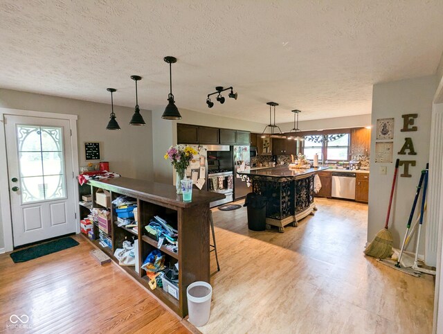 6336 N Carroll Rd, Indianapolis, IN 46235 - kitchen with stainless steel appliances, a textured ceiling, light wood-type flooring, pendant lighting, and a center island