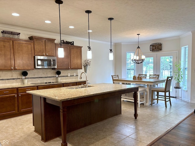 11700 Harvest Moon Dr, Noblesville, IN 46060 - kitchen featuring stainless steel microwave, tasteful backsplash, ornamental molding, a kitchen island with sink, and light stone countertops