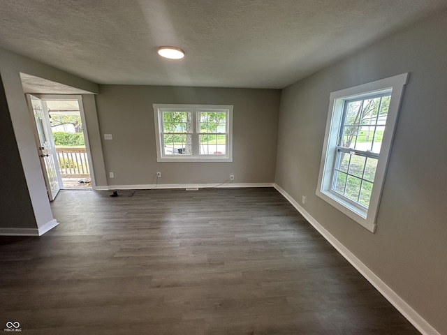 906 N Wabash Ave, Hartford City, IN 47348 - empty room featuring plenty of natural light, dark wood-style floors, baseboards, and a textured ceiling