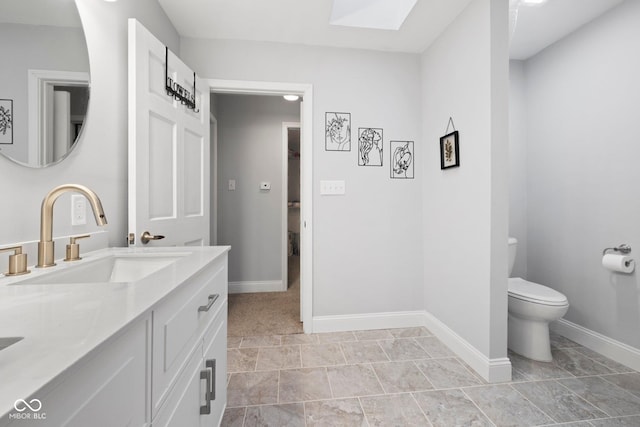 213 Terre Vista Dr, Terre Haute, IN 47803 - bathroom featuring double vanity, toilet, a skylight, and baseboards