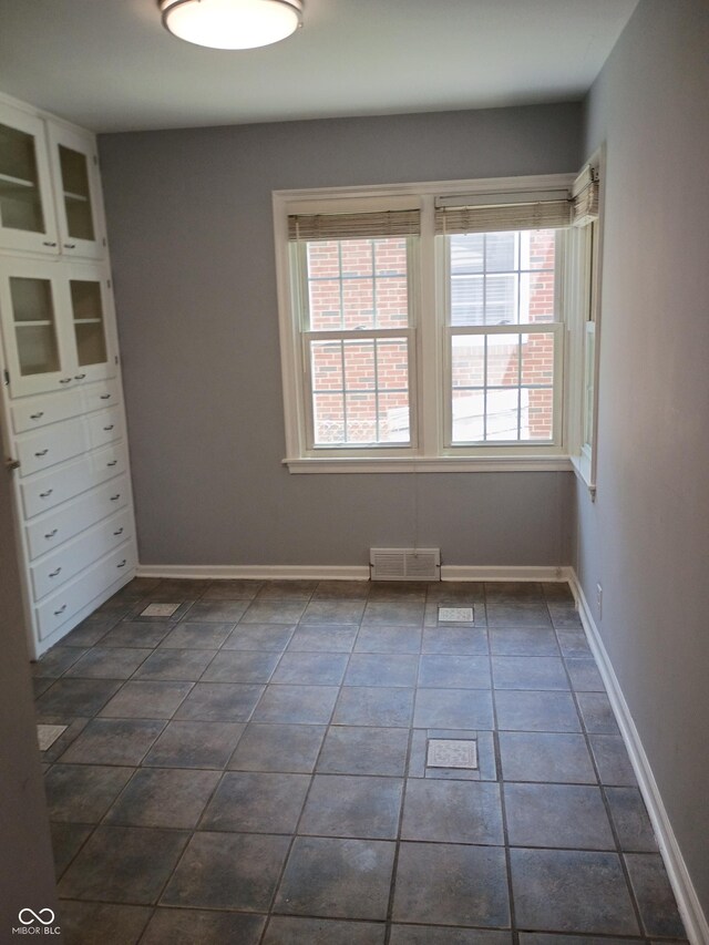 1008 E 61st St, Indianapolis, IN 46220 - empty room with dark tile patterned floors and baseboards
