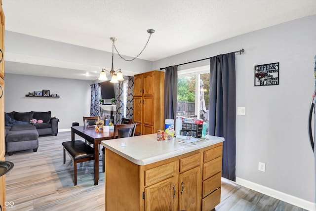 15264 Ten Point Dr, Noblesville, IN 46060 - kitchen featuring light wood-style floors, baseboards, light countertops, decorative light fixtures, and a textured ceiling