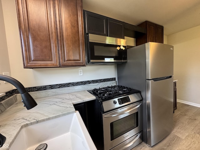 409 Parkway St, Whiteland, IN 46184 - kitchen with stainless steel appliances, light wood finished floors, a sink, dark brown cabinetry, and baseboards