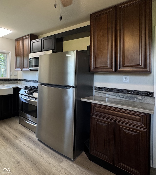 409 Parkway St, Whiteland, IN 46184 - kitchen featuring appliances with stainless steel finishes, light wood-style floors, dark brown cabinets, and a sink