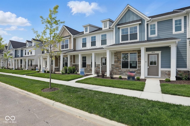 3931 Wren Dr, Brownsburg, IN 46112 - townhome / multi-family property with board and batten siding, a front yard, covered porch, a residential view, and stone siding