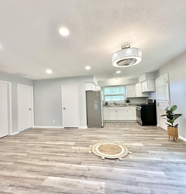 3594 Roland Dr, Kingman, IN 47952 - kitchen featuring appliances with stainless steel finishes, a sink, light wood finished floors, white cabinets, and baseboards