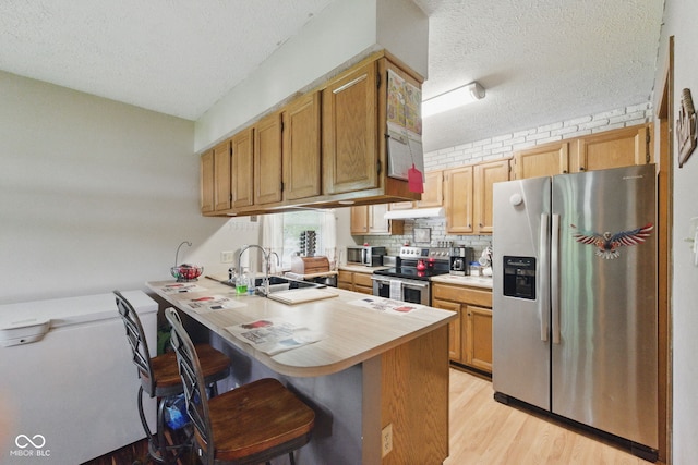 9130 E 18th St, Indianapolis, IN 46229 - kitchen featuring stainless steel appliances, a textured ceiling, a peninsula, a sink, and light countertops