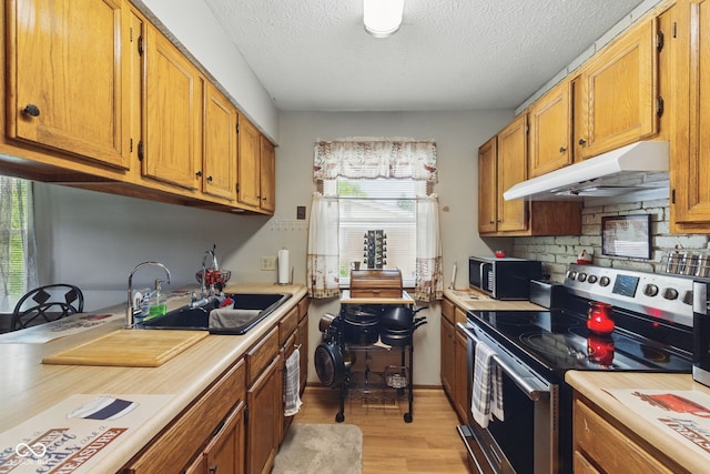 9130 E 18th St, Indianapolis, IN 46229 - kitchen with appliances with stainless steel finishes, under cabinet range hood, light countertops, light wood-style floors, and a textured ceiling